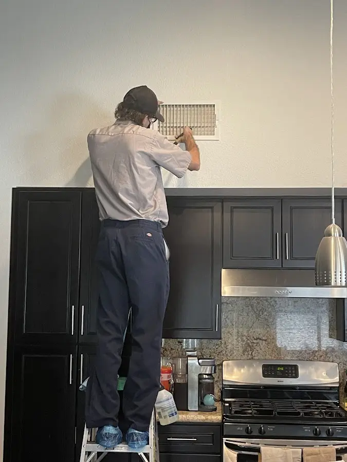 Technician inspecting an air vent during HVAC service in Winston-Salem